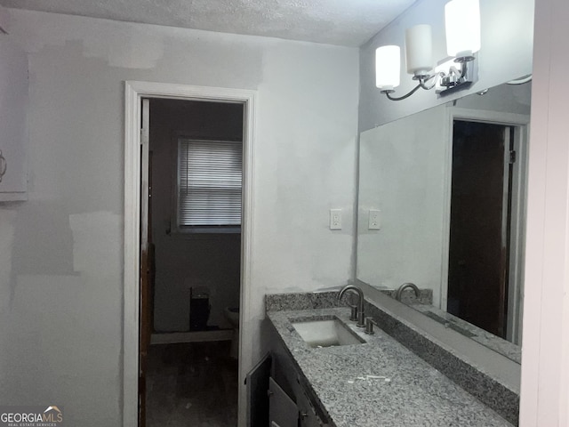 bathroom with toilet, vanity, a textured ceiling, and an inviting chandelier