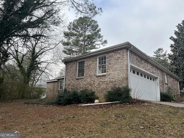 view of home's exterior with concrete driveway, brick siding, and an attached garage