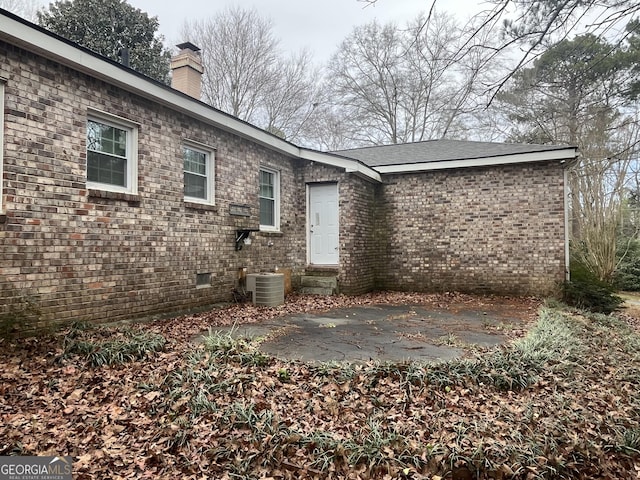 back of house featuring central AC unit, a patio, a chimney, crawl space, and brick siding