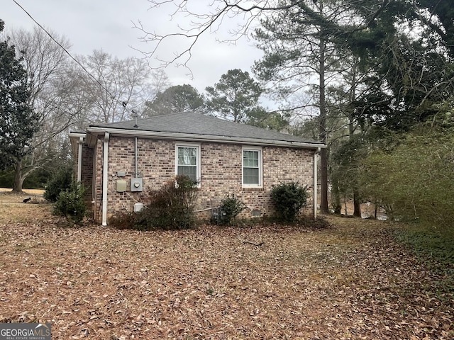 view of home's exterior featuring crawl space, a shingled roof, and brick siding