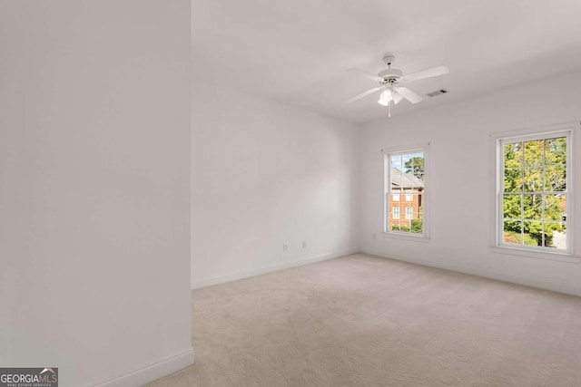 spare room featuring light colored carpet, visible vents, plenty of natural light, and baseboards