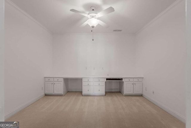 unfurnished office with ornamental molding, built in desk, baseboards, and light colored carpet