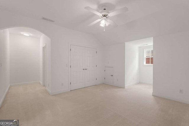unfurnished bedroom with arched walkways, light carpet, visible vents, and baseboards