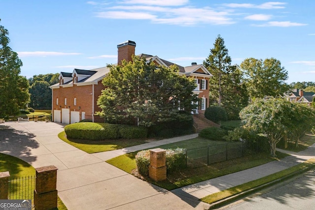 view of front of house featuring a garage, driveway, a front lawn, and a fenced front yard