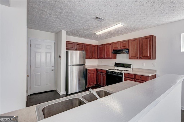 kitchen with visible vents, freestanding refrigerator, gas stove, a sink, and under cabinet range hood