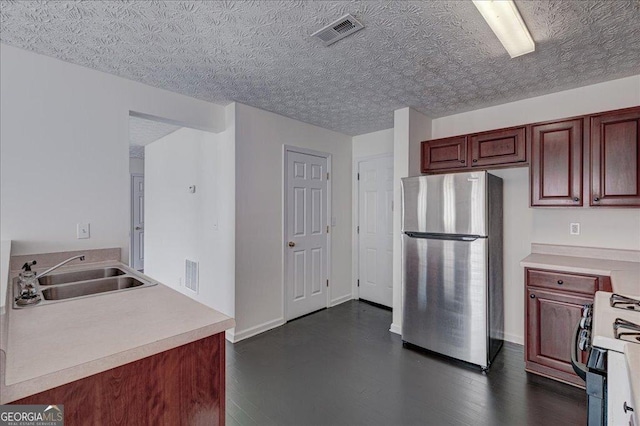 kitchen with freestanding refrigerator, visible vents, a sink, and gas range