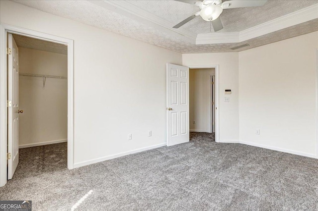 unfurnished bedroom featuring baseboards, visible vents, carpet, a walk in closet, and a textured ceiling