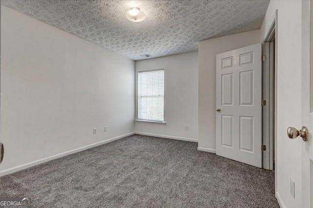 unfurnished bedroom featuring a textured ceiling, carpet flooring, visible vents, and baseboards