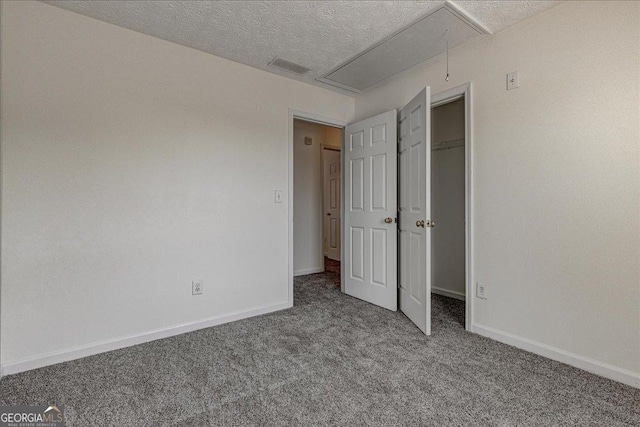 unfurnished bedroom featuring attic access, visible vents, baseboards, carpet, and a textured ceiling