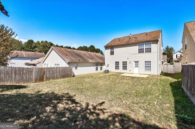 back of house featuring a fenced backyard, central AC, and a lawn