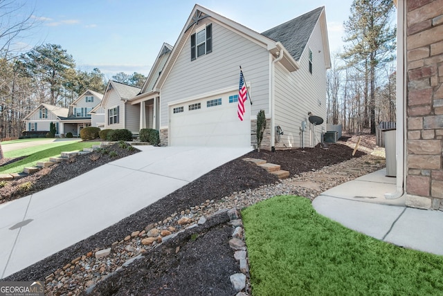 view of property exterior with a garage, concrete driveway, central AC unit, and stone siding