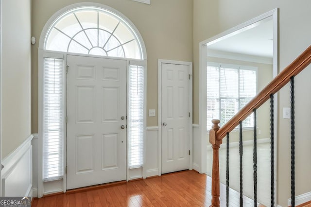 foyer entrance featuring light wood-type flooring, stairway, and ornamental molding