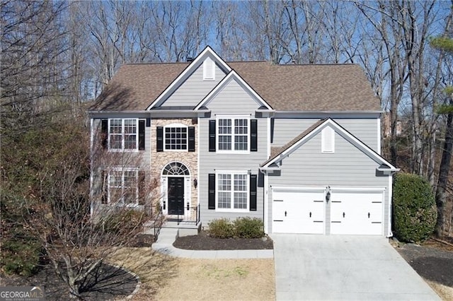 colonial home featuring a garage, driveway, and a shingled roof