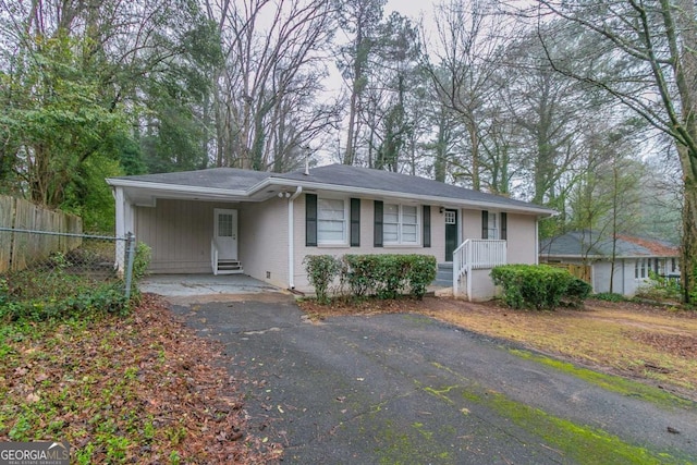 ranch-style home with a carport, brick siding, driveway, and fence