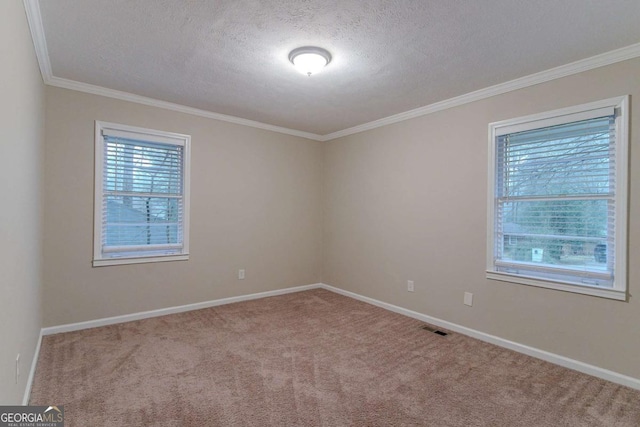 unfurnished room featuring carpet floors, visible vents, crown molding, and baseboards