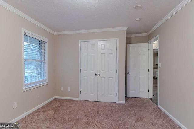 unfurnished bedroom with crown molding, a textured ceiling, baseboards, and carpet flooring