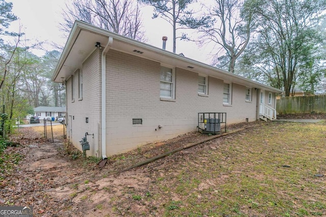 view of home's exterior featuring crawl space, fence, cooling unit, and brick siding