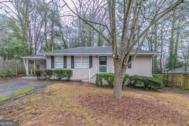 single story home featuring a carport, brick siding, fence, and aphalt driveway