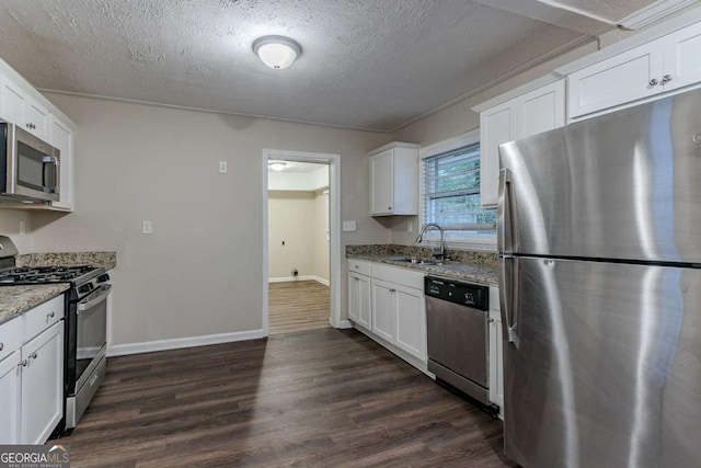 kitchen featuring appliances with stainless steel finishes, dark wood-style flooring, a sink, and light stone countertops