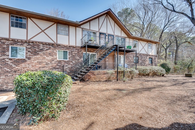 back of property with stairs, brick siding, and stucco siding