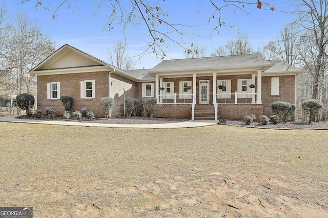 ranch-style house featuring a porch, brick siding, and a front lawn