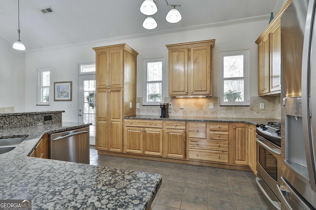 kitchen featuring tasteful backsplash, visible vents, dark tile patterned flooring, decorative light fixtures, and stainless steel appliances