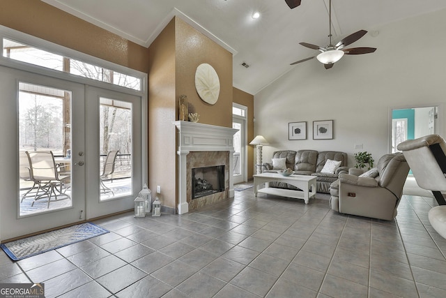 tiled living room featuring ceiling fan, high vaulted ceiling, a fireplace, visible vents, and french doors