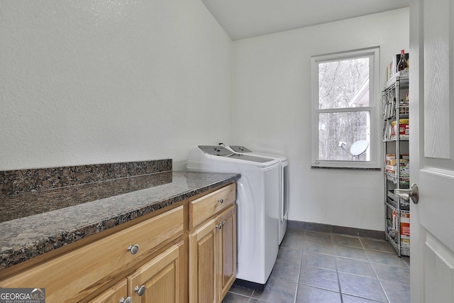 clothes washing area with baseboards, dark tile patterned flooring, cabinet space, and washer and dryer