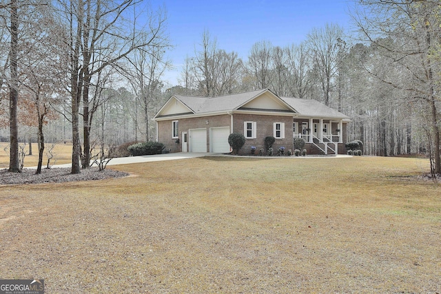 view of front of property with brick siding, a porch, a front yard, a garage, and driveway