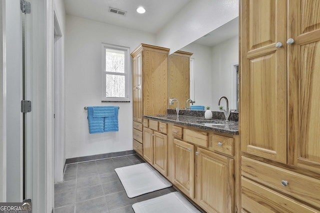 bathroom with double vanity, a sink, baseboards, and tile patterned floors