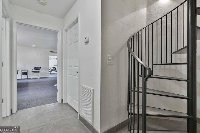 stairway with carpet, tile patterned flooring, visible vents, and baseboards