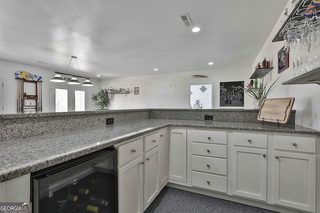 kitchen featuring beverage cooler, visible vents, white cabinets, a textured ceiling, and french doors