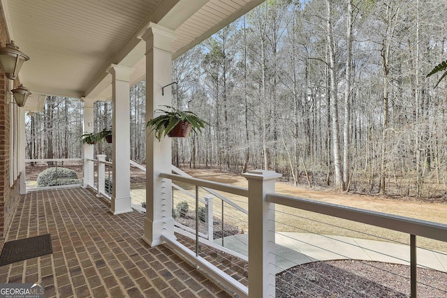 wooden deck featuring covered porch and a view of trees