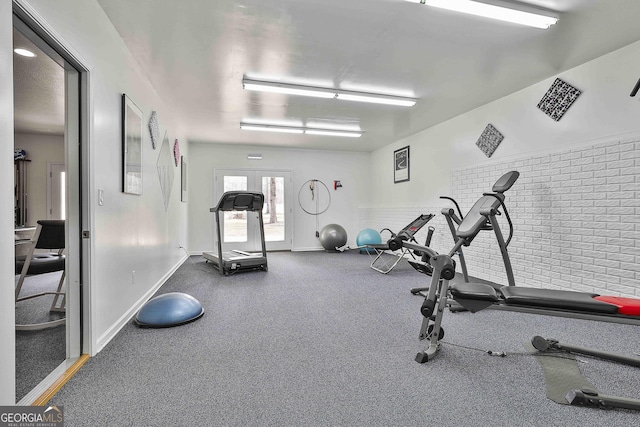 workout area featuring brick wall and baseboards