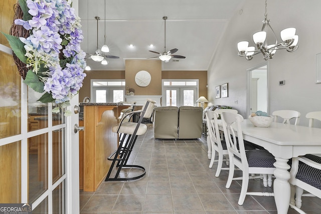 dining area with lofted ceiling, tile patterned floors, ceiling fan with notable chandelier, and french doors