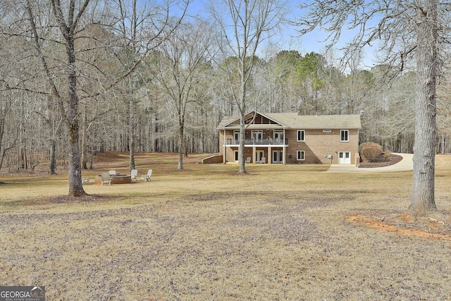 view of front of house with a forest view, a front lawn, and brick siding