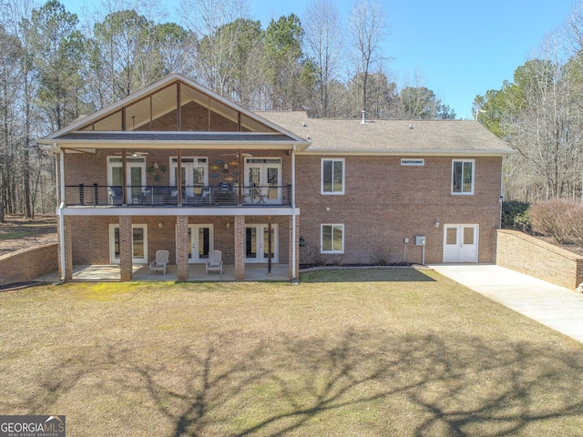 back of property with a lawn, a patio, a balcony, french doors, and brick siding