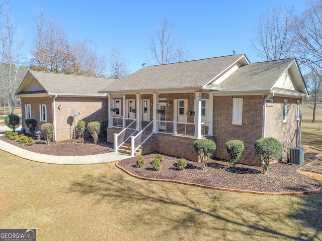 ranch-style house featuring brick siding, a porch, a shingled roof, central AC, and a front lawn