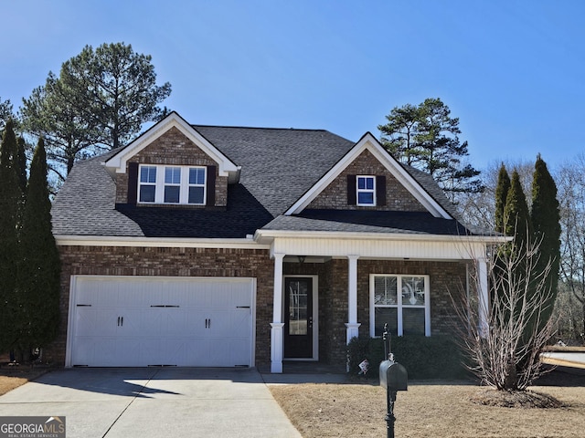 view of front of house with a shingled roof, brick siding, driveway, and a porch