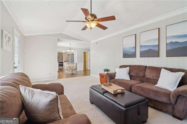 living area featuring lofted ceiling, ornamental molding, and ceiling fan with notable chandelier