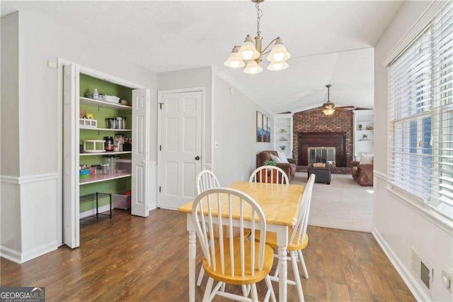 dining area with lofted ceiling, built in shelves, a fireplace, and wood finished floors