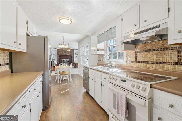 kitchen with appliances with stainless steel finishes, white cabinets, a sink, wood finished floors, and under cabinet range hood