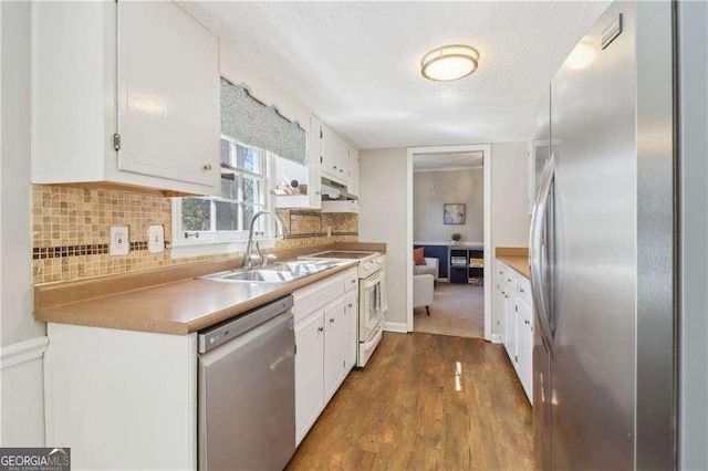 kitchen with stainless steel appliances, tasteful backsplash, white cabinets, a sink, and under cabinet range hood