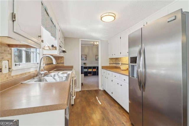 kitchen featuring tasteful backsplash, white cabinets, a sink, and stainless steel fridge with ice dispenser