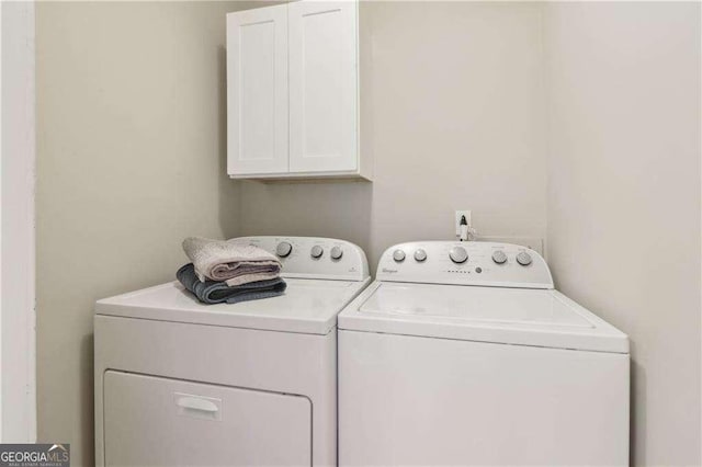 clothes washing area featuring cabinet space and washer and clothes dryer