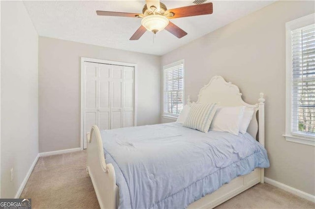 carpeted bedroom featuring multiple windows, a closet, a ceiling fan, and baseboards