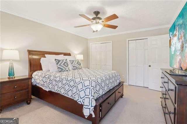 bedroom with crown molding, a ceiling fan, two closets, and light colored carpet