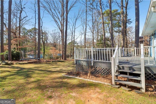 view of yard featuring a trampoline and a wooden deck