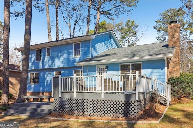 back of property with a chimney and a deck