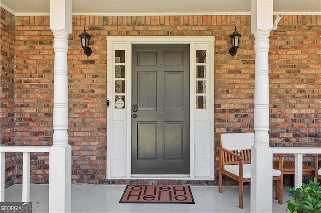 entrance to property with brick siding and a porch